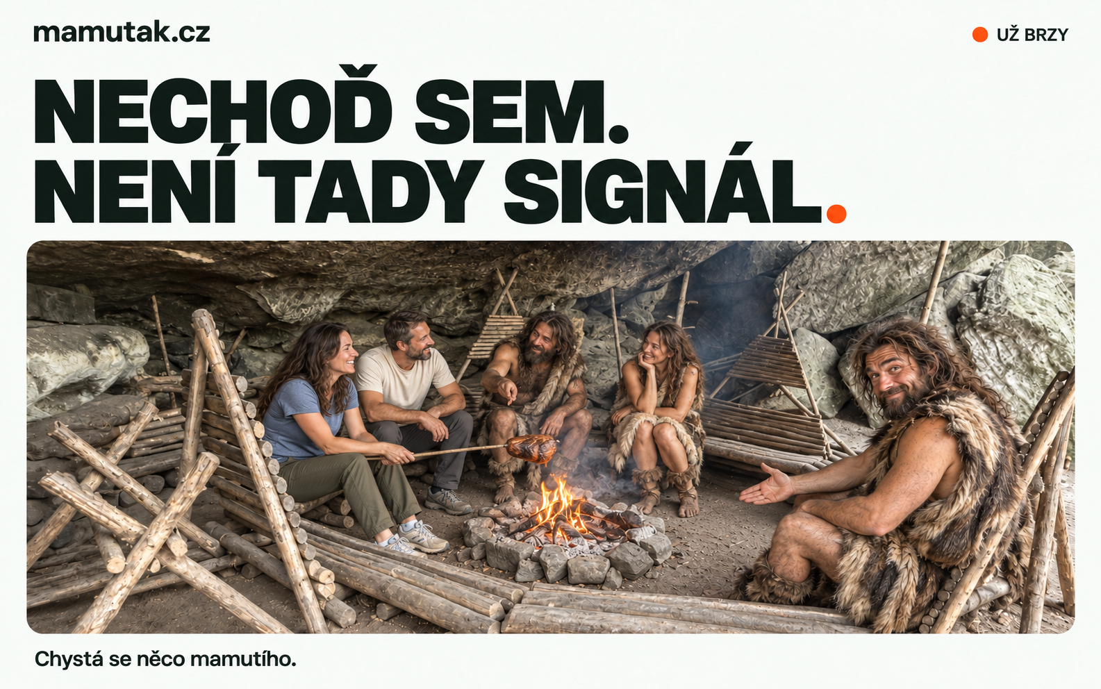 Moderní návštěvníci a pravěká tlupa se baví u ohně pod převisem Mamuťáku. Usměvavý pračlověk vpravo zve na volné místo vedle sebe.